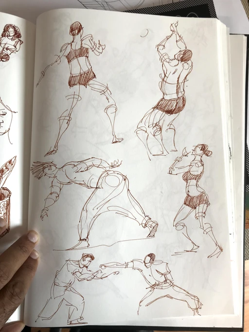 A sketchbook held open on a page of ink gesture figures